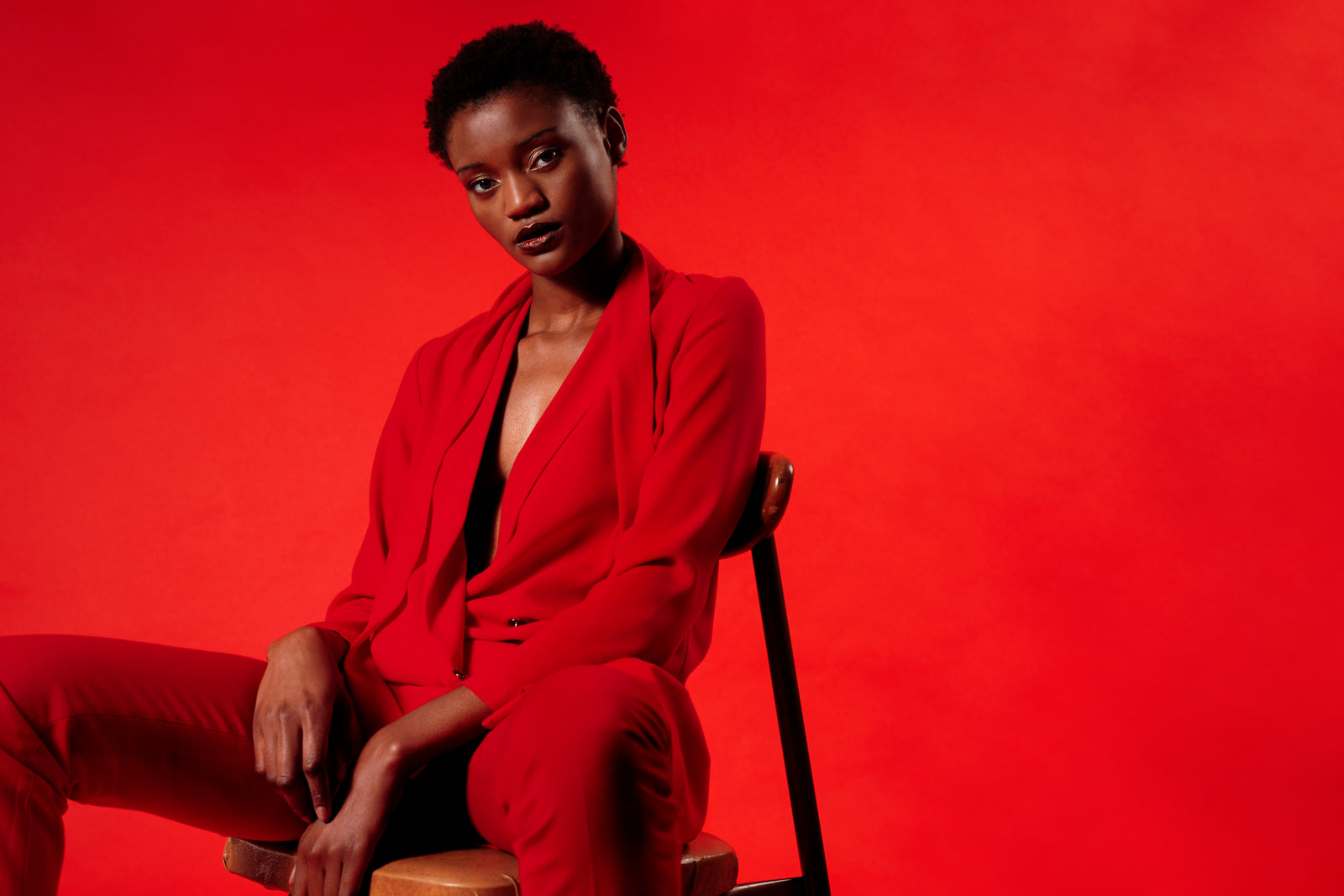 Woman in a red suit seated against a red background